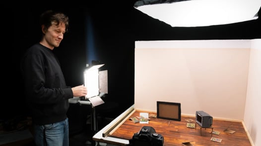 En man står framför en kamera och håller i en lampa.