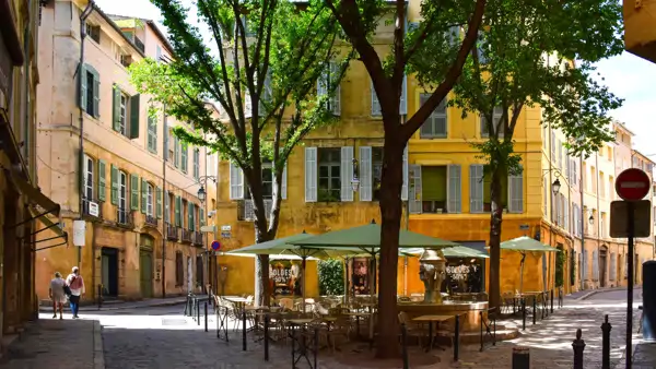 En gata med bord och parasoller på sidan av den i Aix-en-Provence. Gå en terminskurs i franska i Provence i Frankrike.