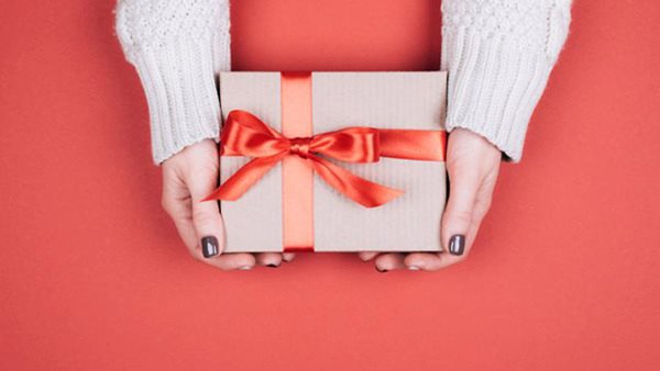 Kvinna som håller fram ett paket - Presentkort på Folkuniversitetet
