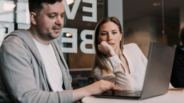 Två personer arbetar tillsammans vid en laptop under en IT-utbildning