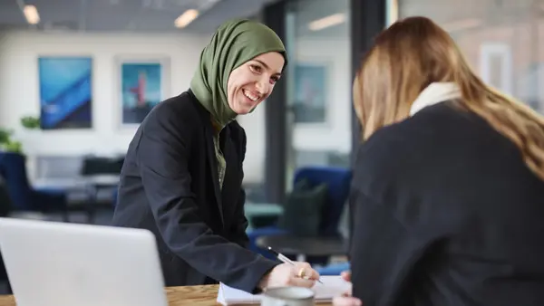 En kvinna sitter vid ett bord med en bärbar dator.