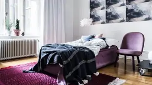 Ett sovrum med en säng, en stol, en matta och tavlor på väggen.