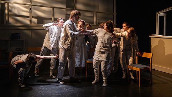 En föreställningar på skolscen med 10 elever i vita kläder. 