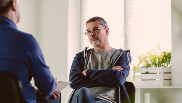 Mature psychotherapist talking with depressed man. Coach is discussing about mental illness with man. They are in meeting in psychotherapeutic office