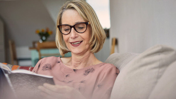 Kvinna med glasögon sitter i soffa och studerar ungerska