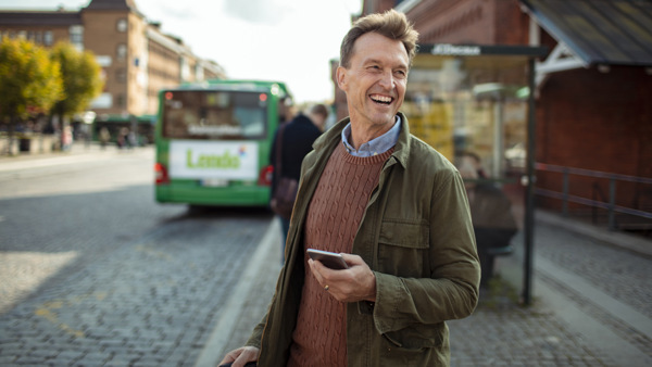 En man står på en gata och håller i en mobiltelefon.