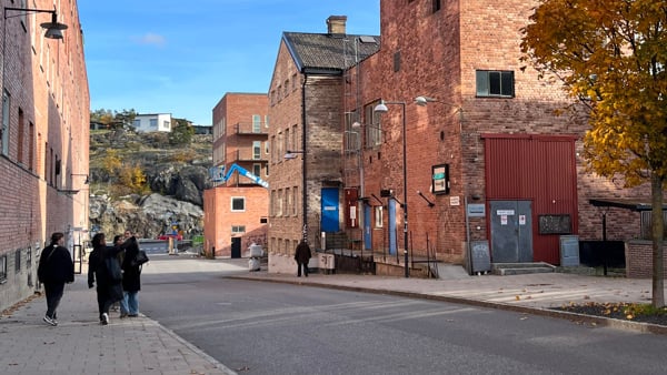 N&aring;gra m&auml;nniskor som g&aring;r l&auml;ngs en gata bredvid h&ouml;ga byggnader.