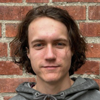 En man som står framför en tegelvägg.