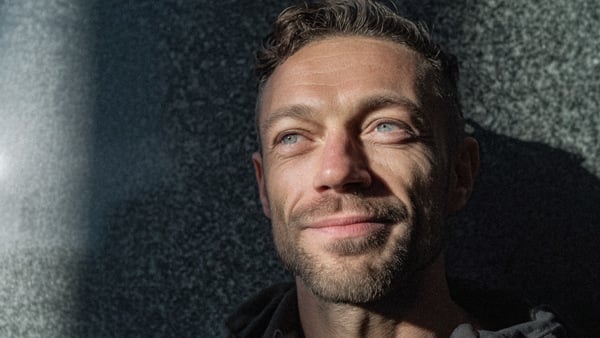 En man med skägg och röd skjorta.