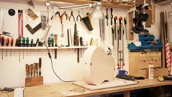 A guitar lies on a workbench.