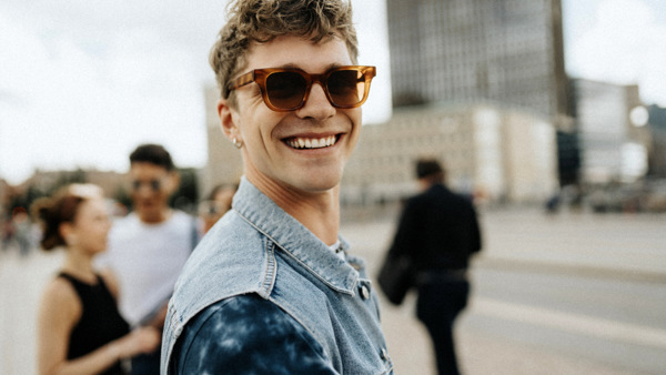 En man med solglasögon står framför en grupp människor.