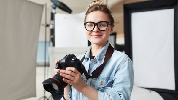 Pretty girl with photocamera shooting in her own photostudio