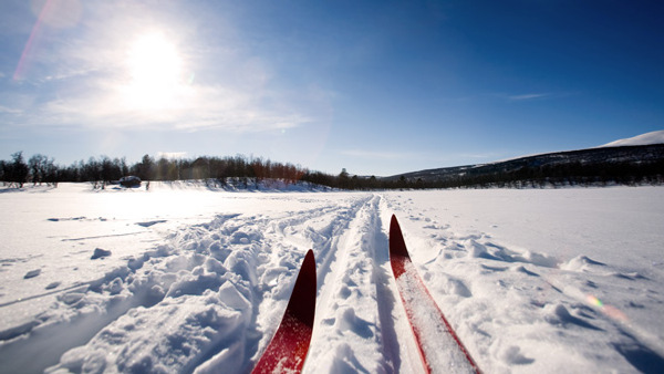Ett par röda skidor som ligger i snö