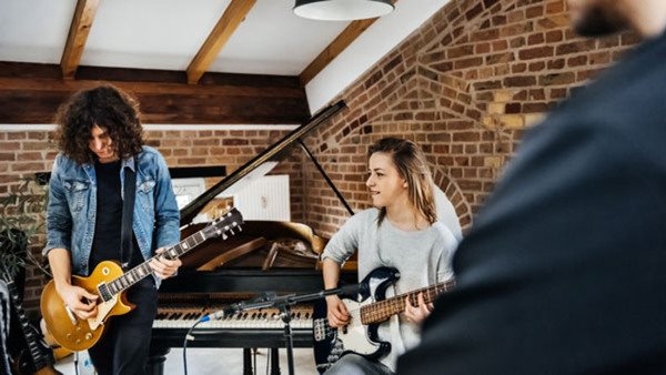 Young members of a band rehearsing in a small studio.