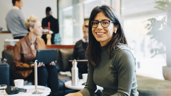 Kvinna i grön tröja och svarta glasögon sitter i en kontorsmiljö 