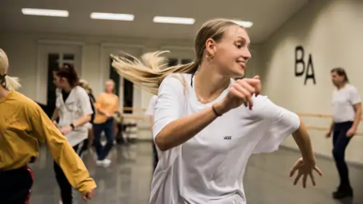 Glad dansare i vit tröja på Balettakademien Stockholm. 