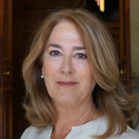 En kvinna i vit klänning ler mot kameran.