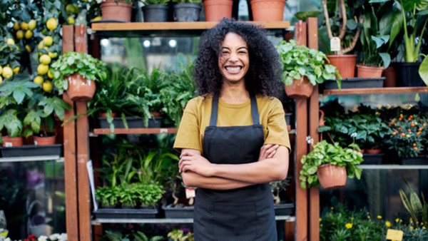Leende kursdeltagare omgiven av krukväxter och plantor - inspirerad av en kurs i botanik