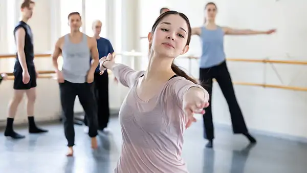 Ung tjej i rosa tröja som dansar på en dansklass på Balettakademien