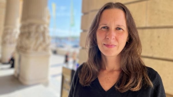 En kvinna står framför en byggnad.