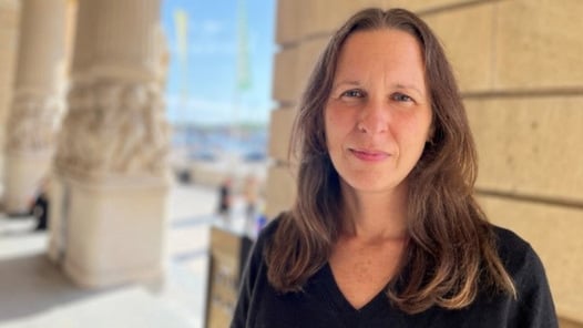 En kvinna står framför en byggnad.