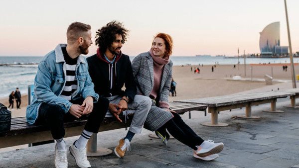 Three happy friends sitting on a bench at the sea