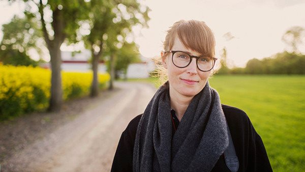 Svenska C1-test. Kvinna med glasögon på grusväg på landet.