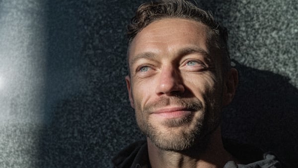 En man med skägg och röd skjorta.