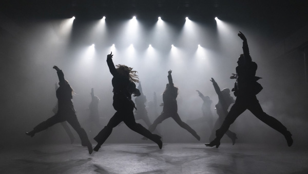 Flera elever på scen, hoppas samtidigt och ljuset visar endast siluetter. 