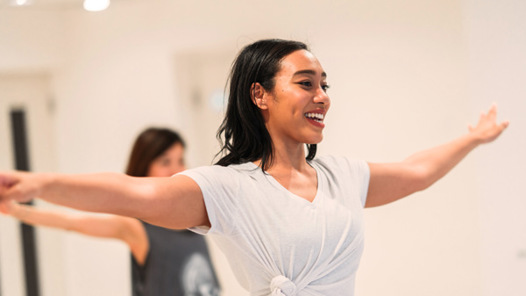 Glad kvinna i vit tröja dansar på Dansstudion i Linköping. 