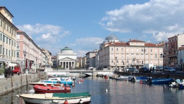 Båtar i en flod i Trieste dit du kan åka för att läsa italienska med oss