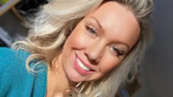 En kvinna med blont h&aring;r ler mot kameran.