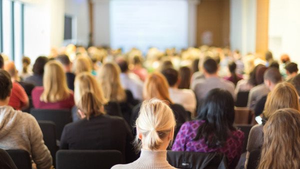 Deltagare lyssnar på föreläsning om samhällsfrågor i fullsatt sal 