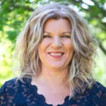 En kvinna som ler och bär en blå blus