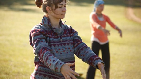 Två deltagare som utövar qigong i en park