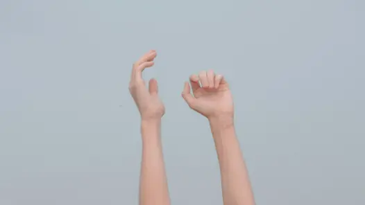 Händer som sträcker sig upp framför en ljus bakgrund.