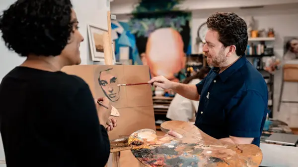 En man målar en kvinnas ansikte på en bit kartong.