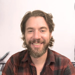 Man med skägg som ler mot kameran