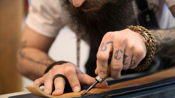 Deltagare täljer trä med kniv på hantverkskurs - gå en kurs i träslöjd!