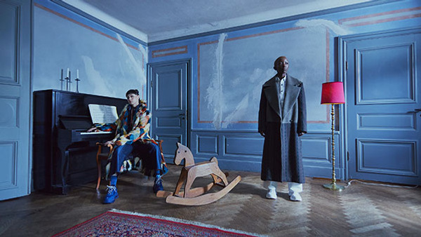 Modeller med kläder i ett blått rum med trägolv, piano och gunghäst