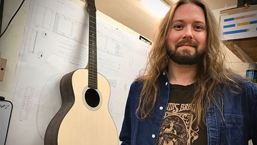 Musikinstrumentakademi-studenten Jonatan Boes ståendes framför en gitarr