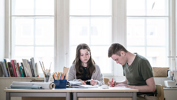 Två elever sitter i en ateljé och jobbar med ett projekt.