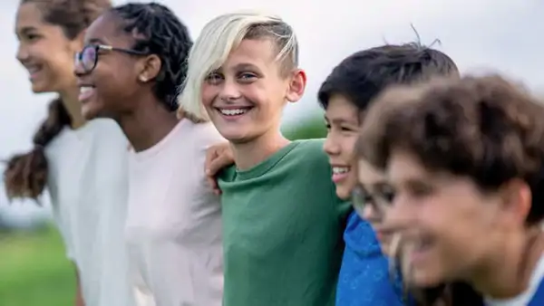 Group of young people smiling and standing arm in arm outdoors