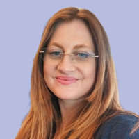 En kvinna med glasögon ler mot kameran.