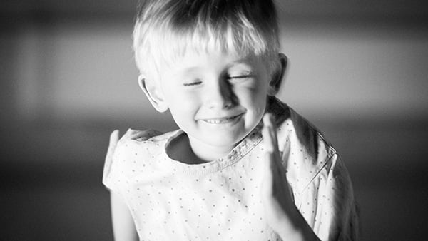 Litet barn som blundar, ler och dansar