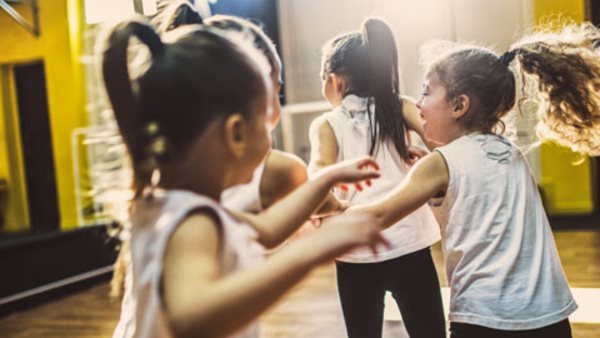 Teacher and group of children exercising dancing and ballet in dance school
