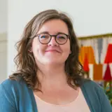 En kvinna står framför en krukväxt.