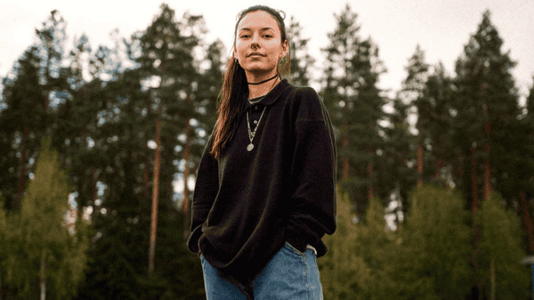 Kvinna står utomhus med en skog i bakgrunden