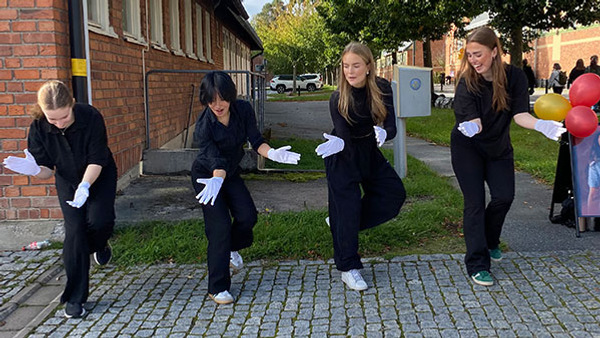 Dansare med svarta kläder och vita handskar dansar utomhus