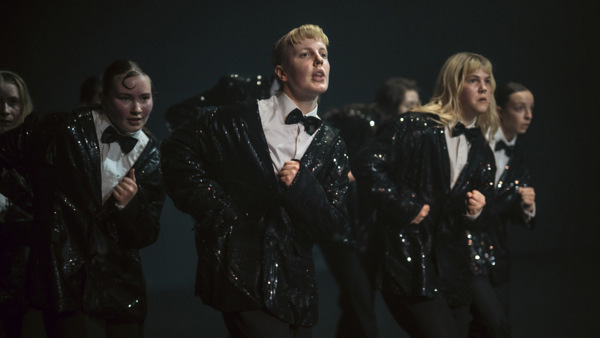 Flera kvinnliga elever på scen Balettakademien Göteborg, iklädda i svarta paljettkavajer. 